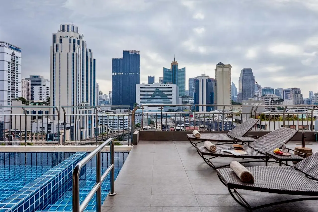 Infinity Pool auf dem Dach des Adelphi Suites Bangkok mit Sonnenliegen und die Skyline von Bangkok-