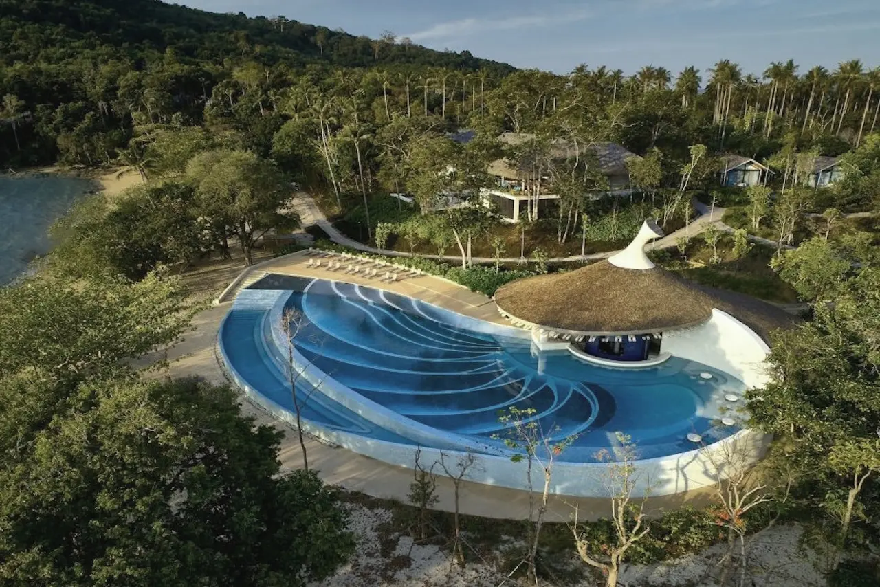 Weitläufige Poollandschaft im Island Escape Burasari auf Phuket mit Blick auf Berge, das Meer und das luxuriöse Hotelresort.
