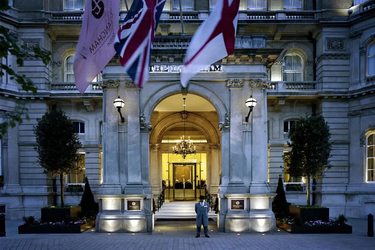 The Langham London, imposante Frontansicht mit britischen Fahnen und Butler in Uniform vor dem Hoteleingang