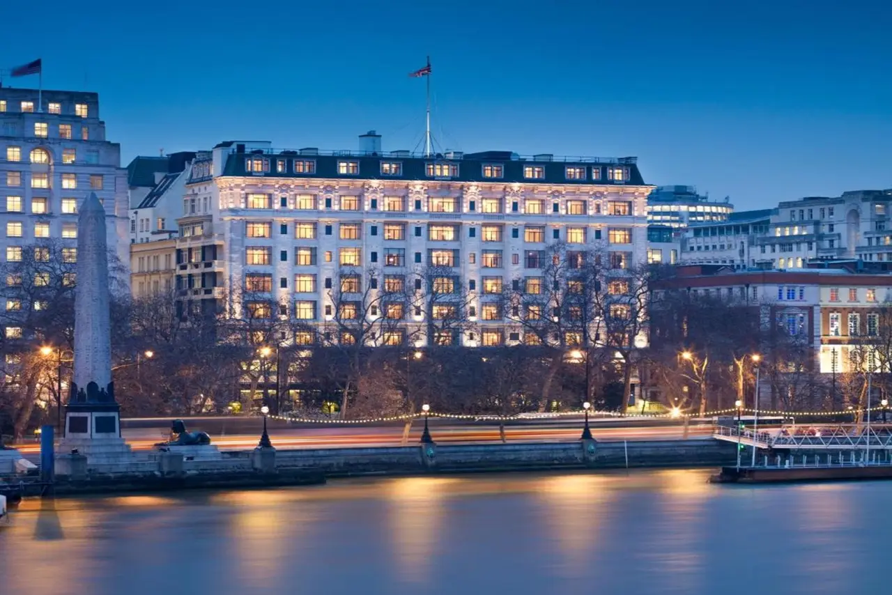 The Savoy London bei Sonnenuntergang, eindrucksvoll beleuchtet, Blick von der Themse mit Skyline